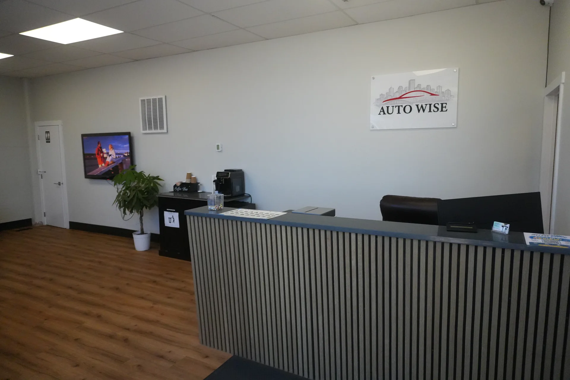 Auto Wise reception desk with the shop logo on the wall and coffee area beside it.