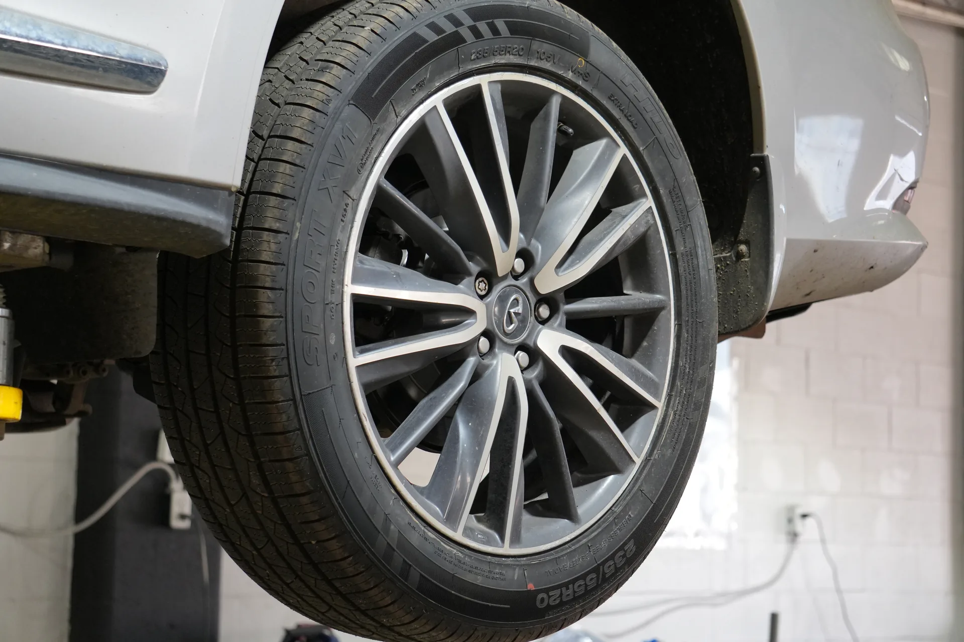 Close-up of the tire and alloy wheel on a vehicle raised inside the workshop.